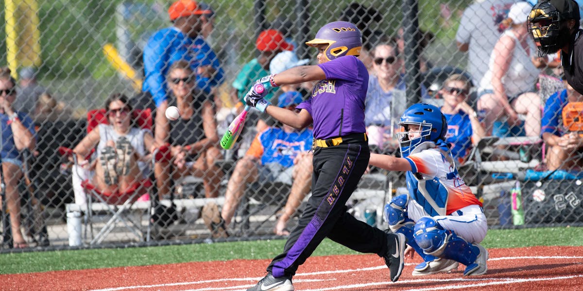 Young players engaged in a baseball game at a sunny outdoor park.