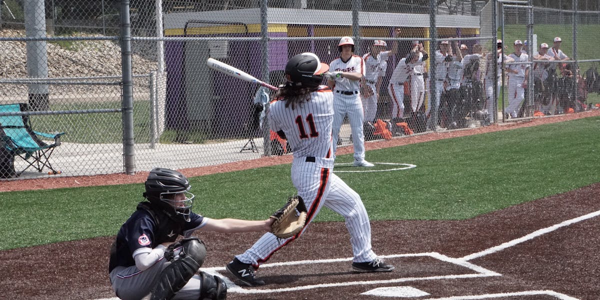Amateur baseball player swinging bat on an outdoor field, showcasing action and co...