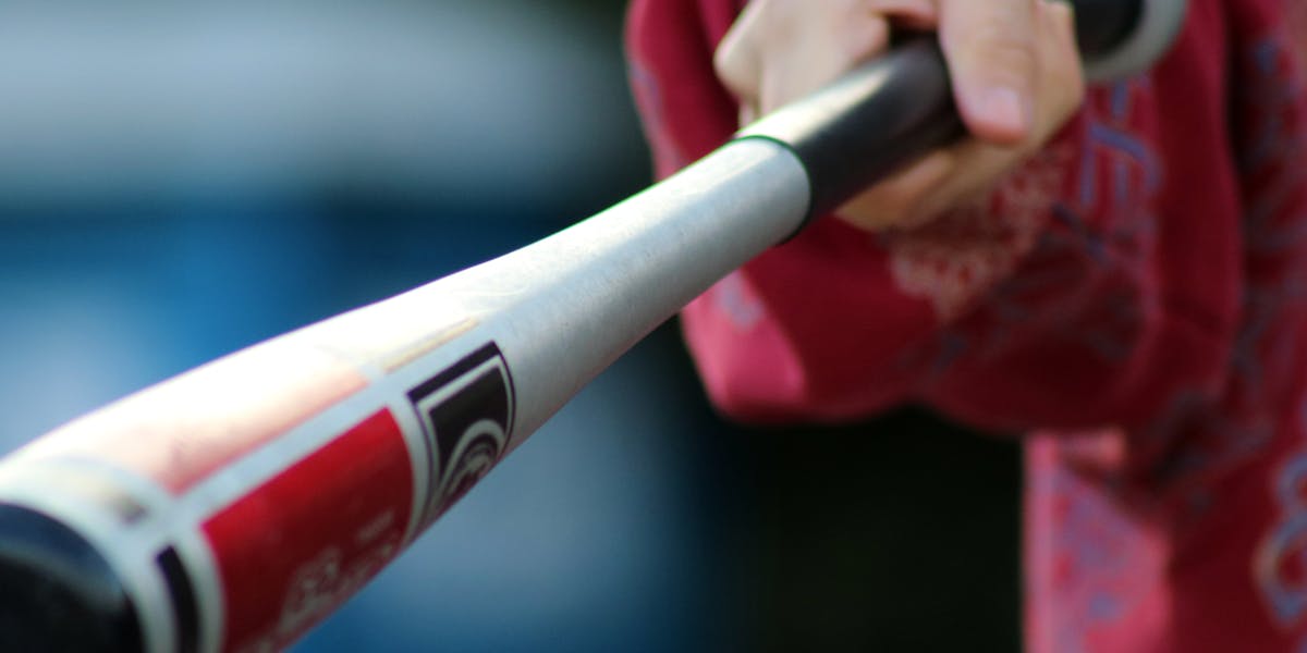 Close-up shot of a hand gripping a baseball bat, showcasing action and sports equi...