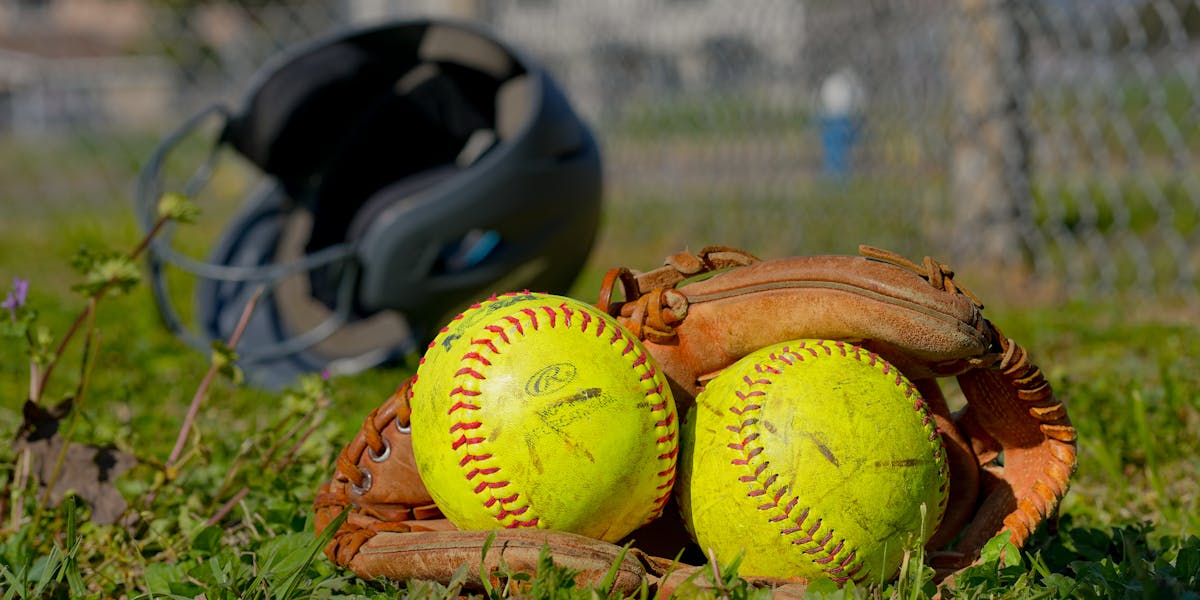 Close-up of baseball gear including balls, glove, and helmet on a field in Houston...