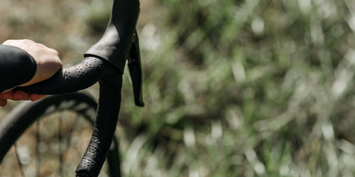 Mountain biker performing a jump during a forest race, wearing red gear and helmet.