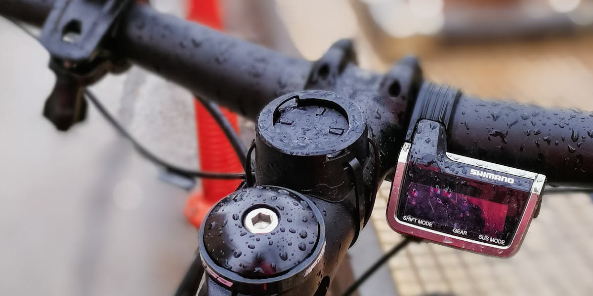 Detailed view of wet bicycle handlebars with raindrops, showcasing outdoor urban