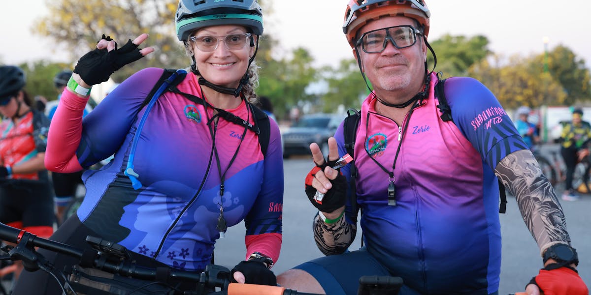 Mountain bike parked by a tree with a colorful helmet hanging from the handlebars.