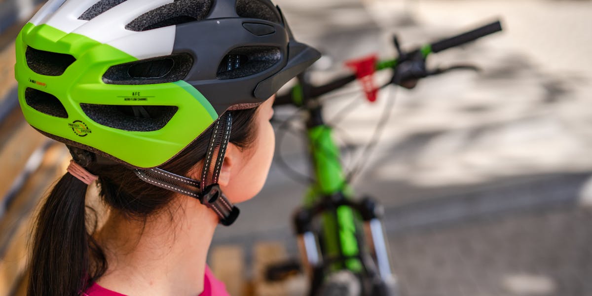Female cyclist wearing a protective helmet prepares for outdoor biking adventure.