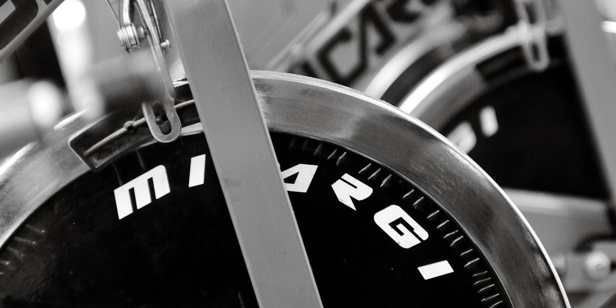 Monochrome close-up of stationary bikes lined up at a gym, highlighting fitness