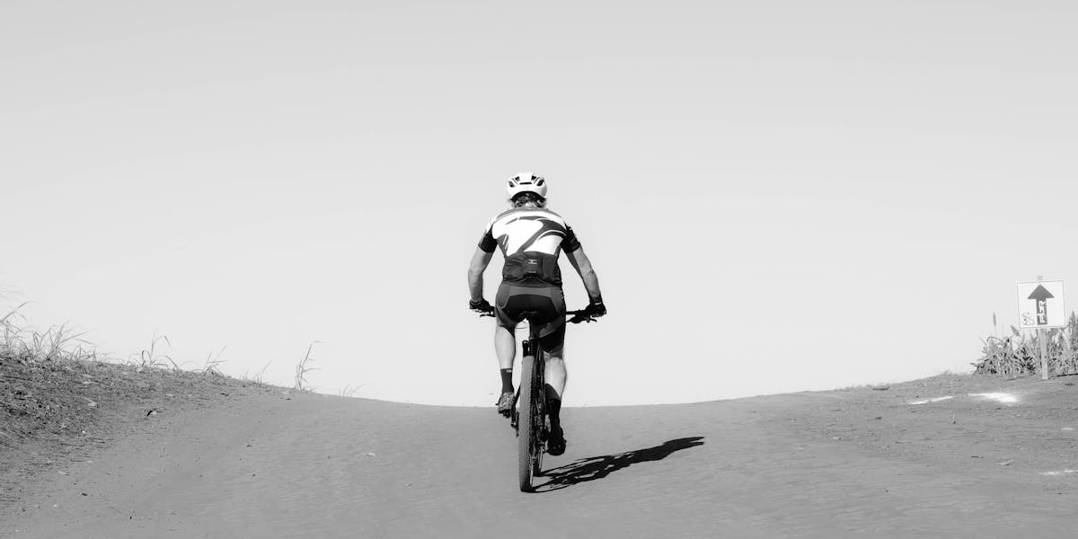 A cyclist ascends a dirt path on a sunny day, capturing the essence of outdoor a