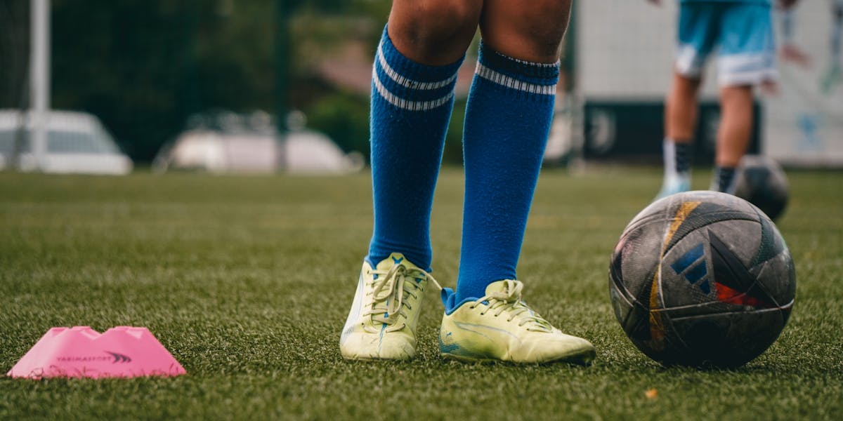 An athlete in a red uniform running with a football during a night game.