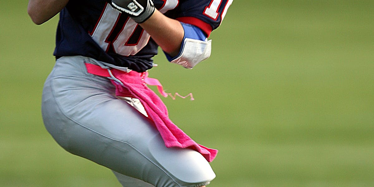 Youth football player catching a pass during a game on a grassy field, showcasin