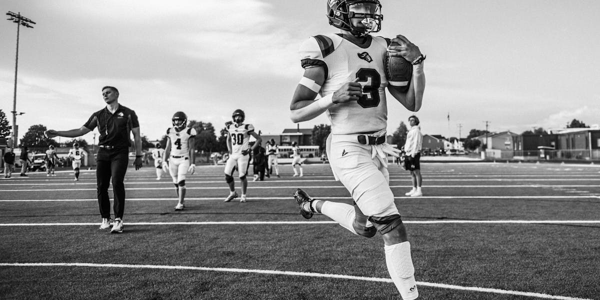 Black and white image of an athlete sprinting on a football field.