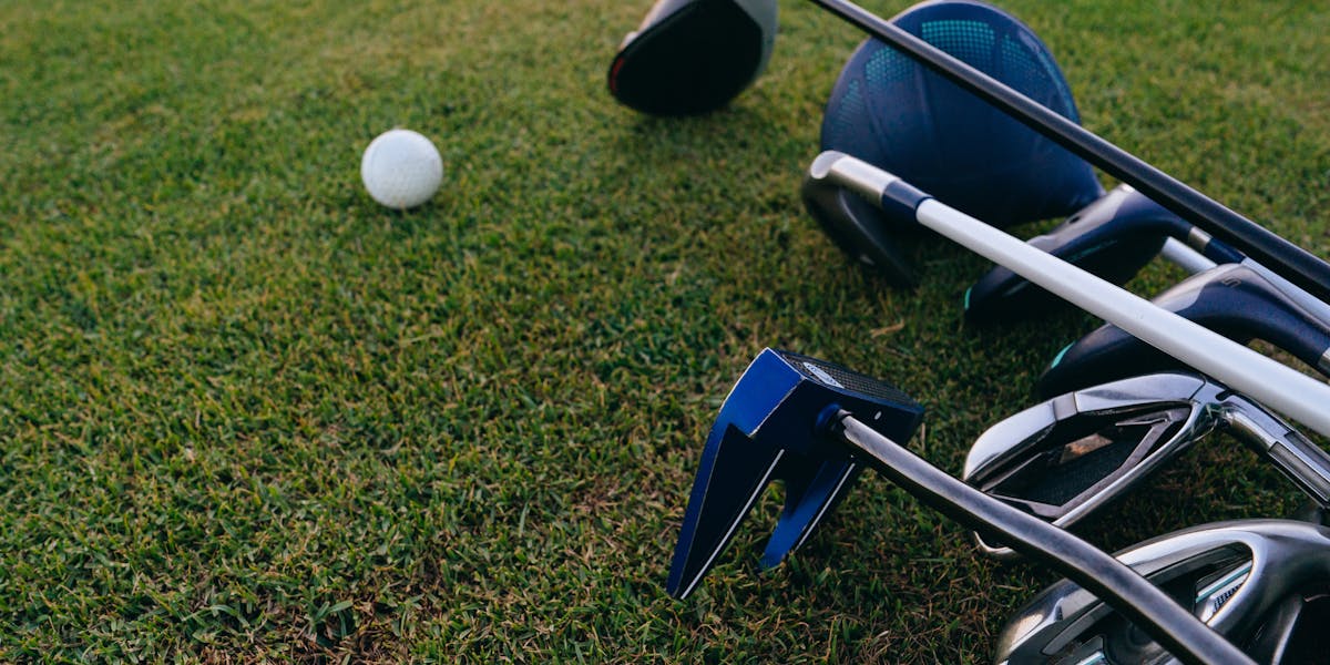 A close-up view of golf clubs and a golf ball on a lush green grass field.