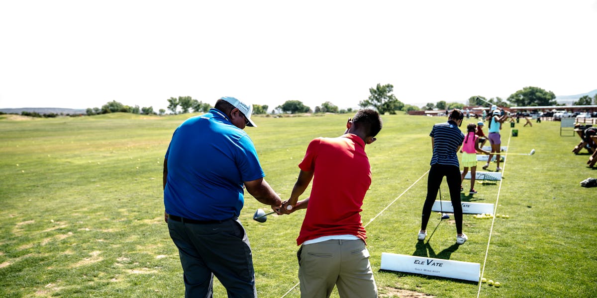 Instructor teaching golf at an outdoor course with students practicing their swi