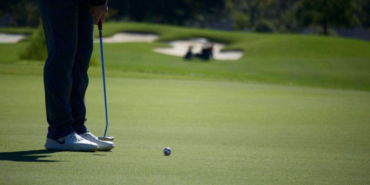Close-up of gray and orange soccer cleats displayed against a bold background, i