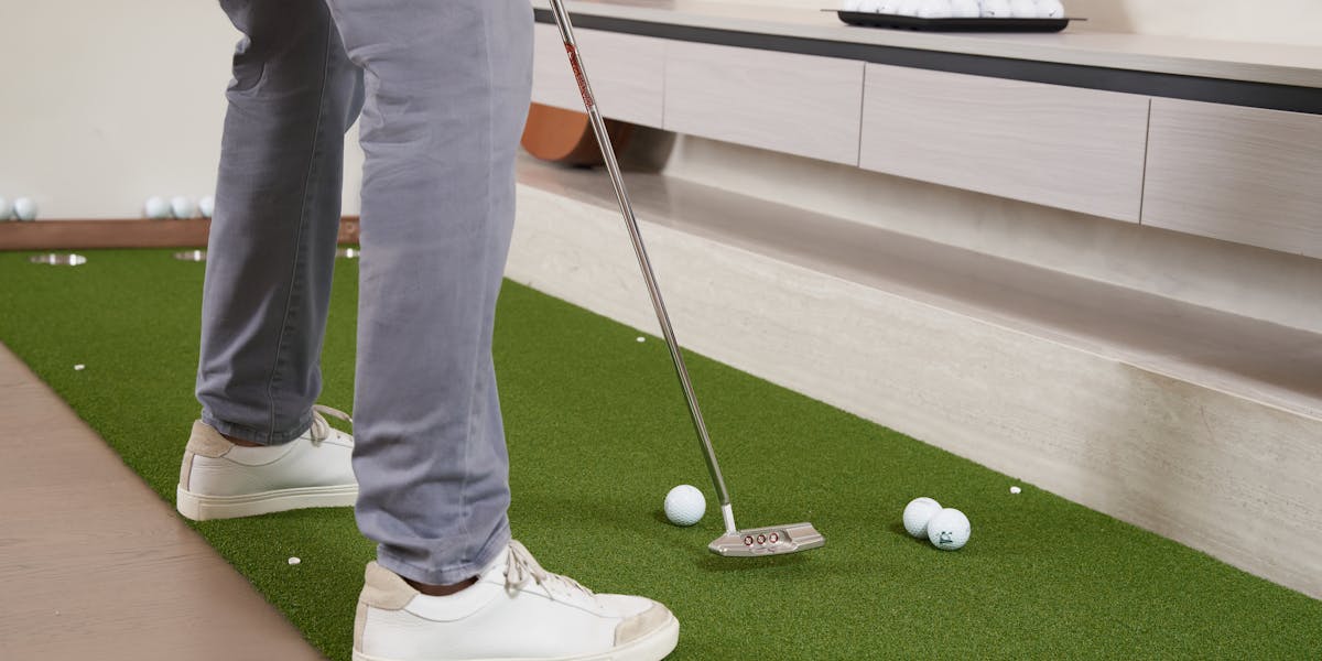 Close-up of a golf training aid featuring artificial turf and golf balls with 'Chi...