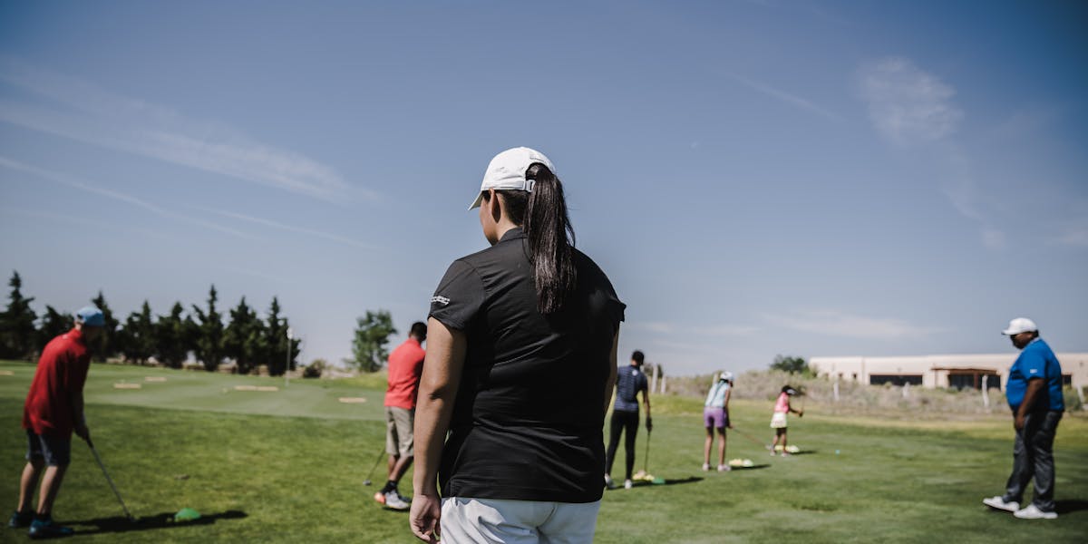 People enjoying a golf lesson on a bright day at the course.