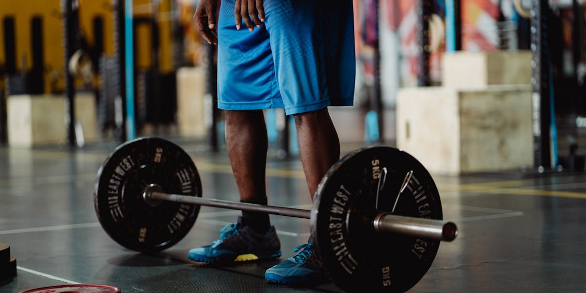 Man preparing for a weightlifting session with barbell and weights in a modern g
