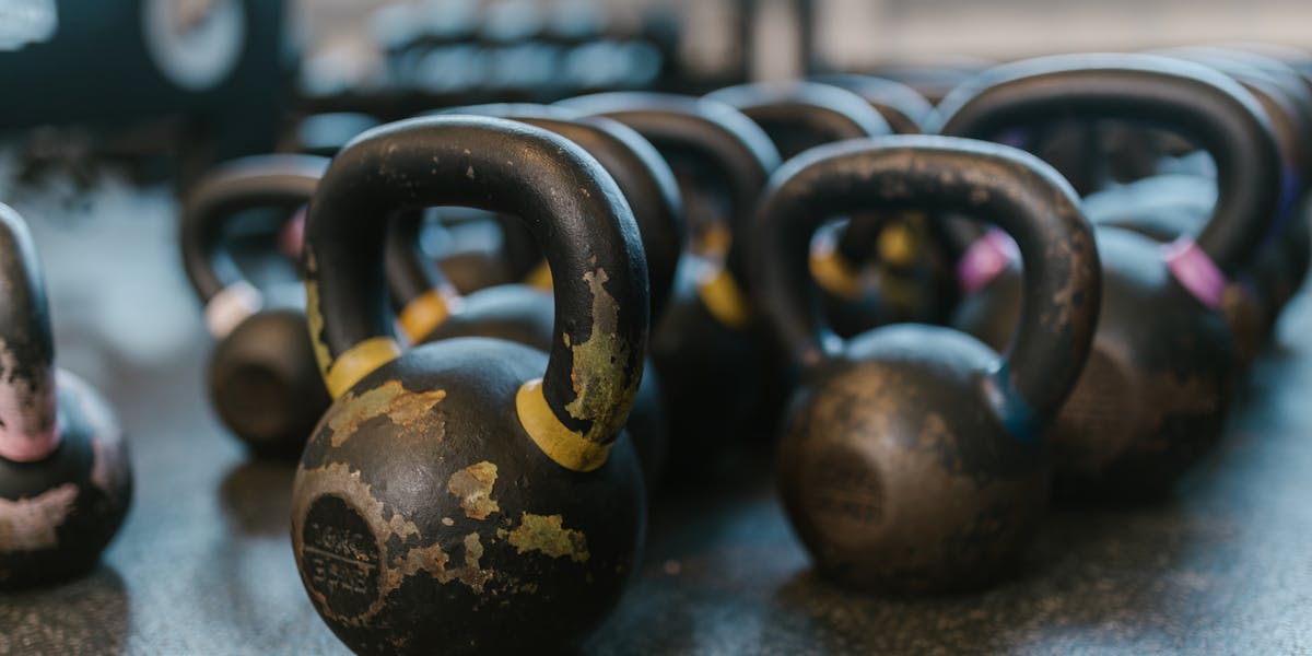 A collection of black kettlebells on a textured gym floor, perfect for fitness ent...