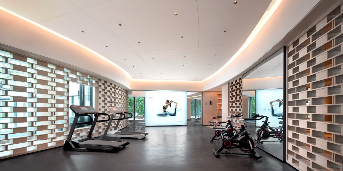 Sleek gym interior with treadmills and stationary bikes, technology-focused design.