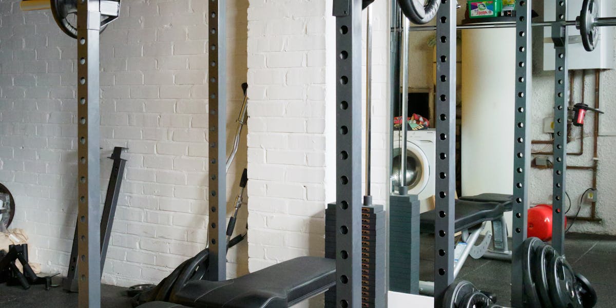 A well-equipped gym featuring a barbell setup with weights and a mirror.