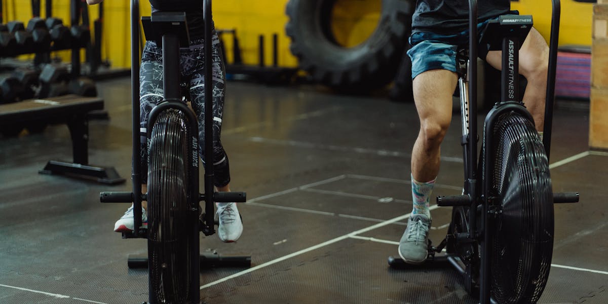 Detailed focus on a black bicycle saddle with gym equipment in the background.