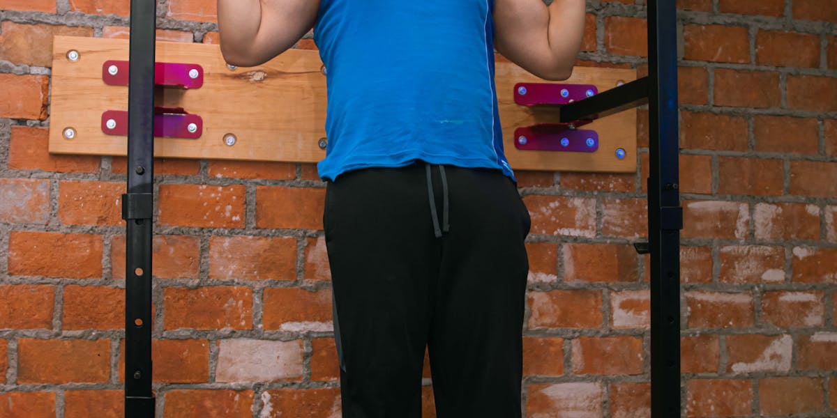 Adult man performing pull-ups on indoor gym bar, showcasing strength and fitness