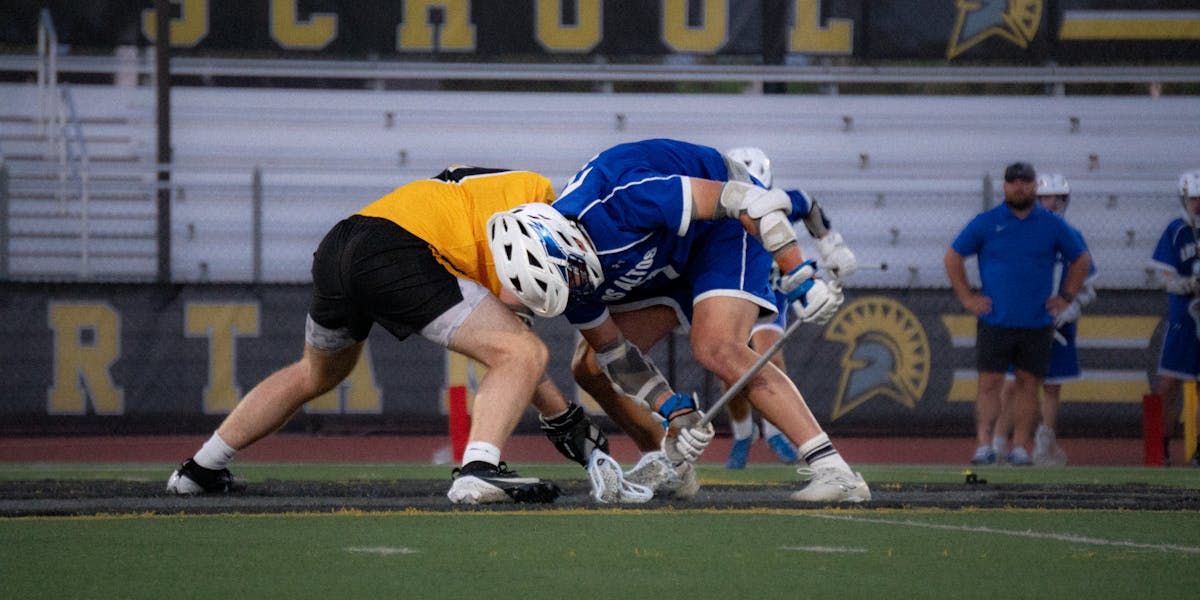 High school lacrosse players face off during an intense game, showcasing sportsman...