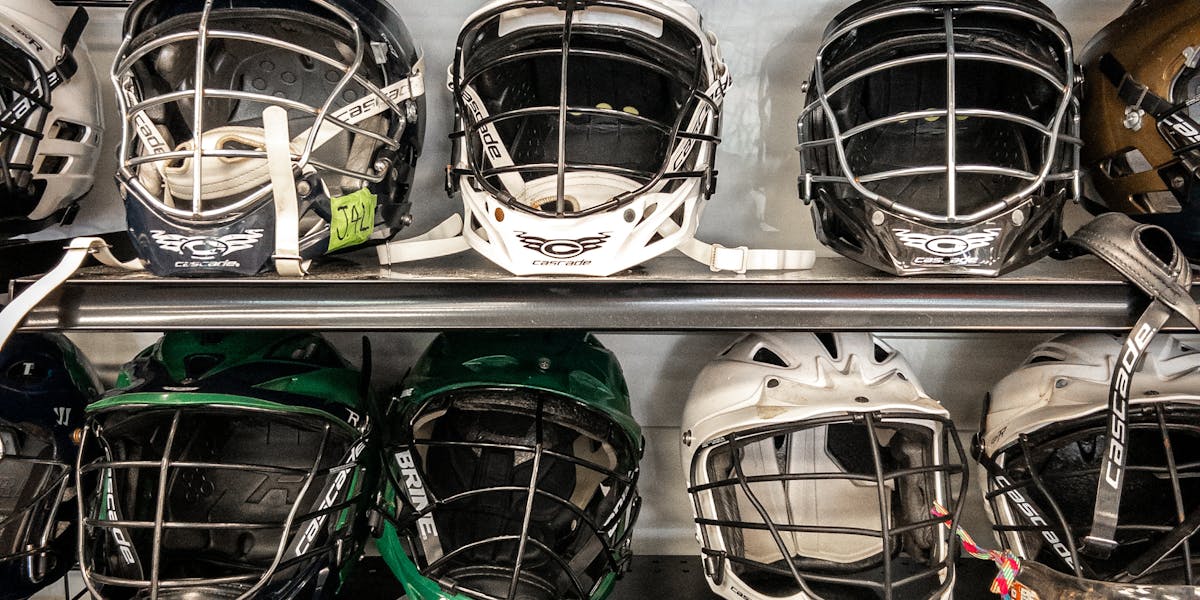 A collection of various lacrosse helmets displayed on shelves in a vertical clos