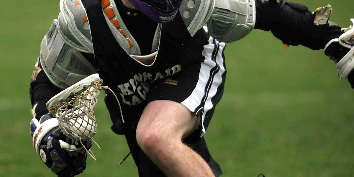 Dynamic shot of a lacrosse player mid-action during a sports game.