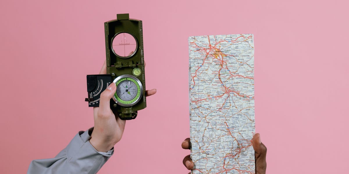 Hands holding a compass and map, symbolizing navigation and direction against a 