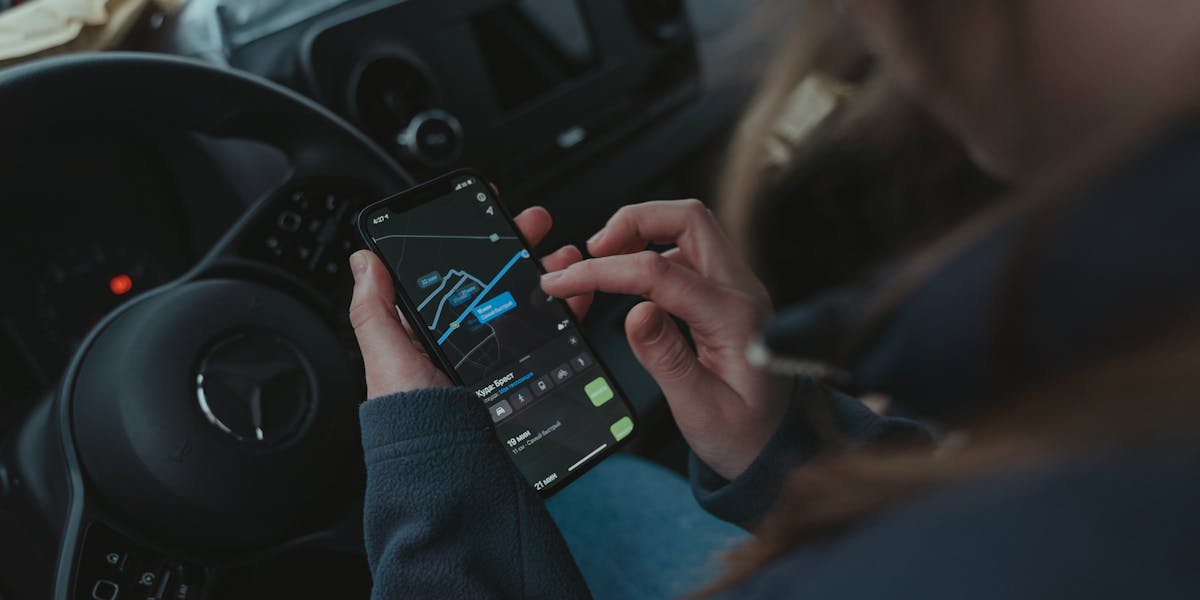 Hand holding smartphone displaying a GPS map application with location data.