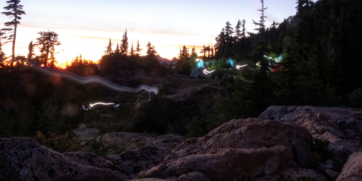 Captivating sunset in the mountains with glowing tents and swirling lights, perf