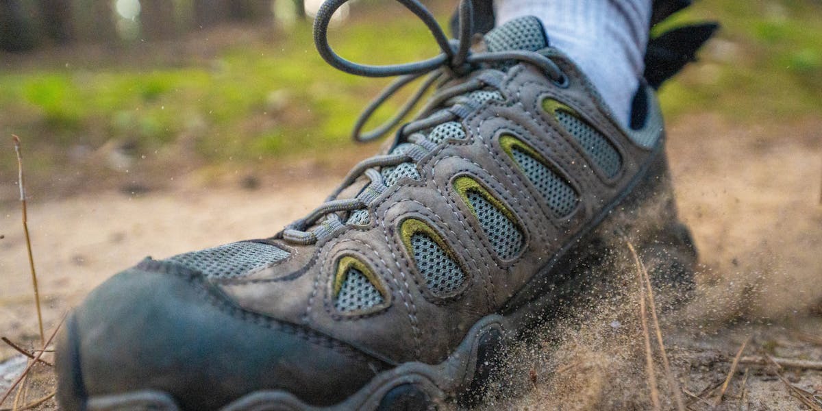 Top view of rain-soaked brown boots standing on lush green grass outdoors, showcas...