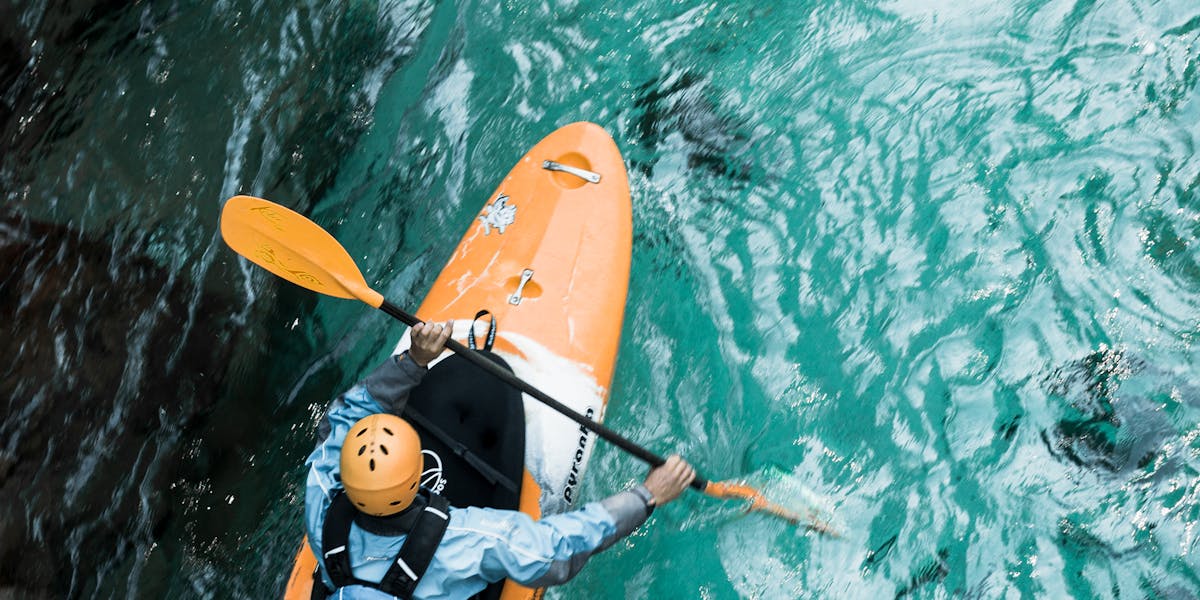 A kayaker paddles through clear turquoise waters, showcasing adventure sports in