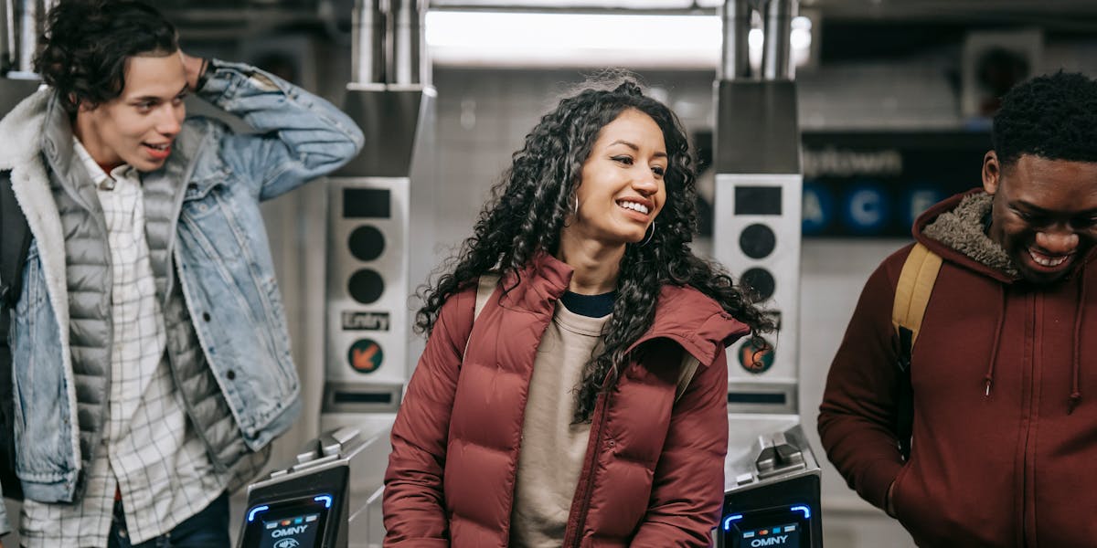 Crop faceless couple in warm clothes standing together while text messaging on phone