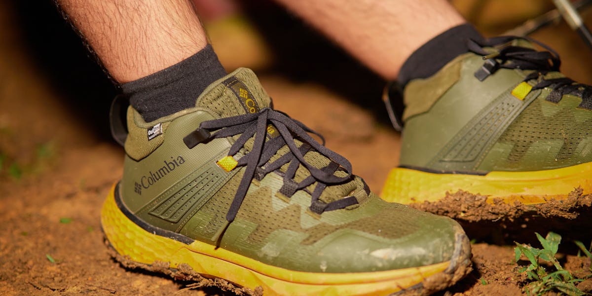 Close-up of green hiking shoes on a muddy path, emphasizing adventure and outdoor ...