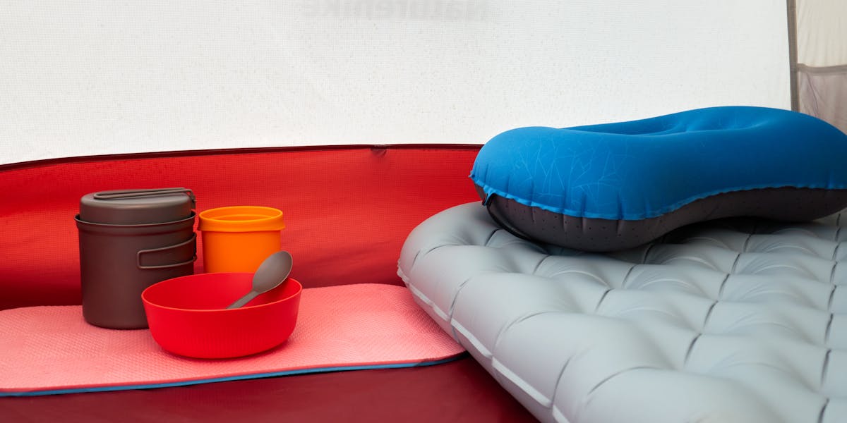 Inside a tent with inflatable pillow, cookware, and sleeping pad, ideal for camp