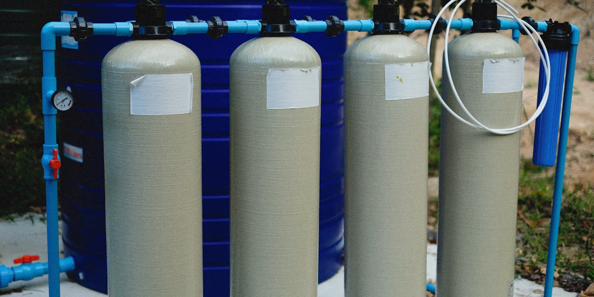 Close-up of hands filling a reusable water bottle at an indoor kitchen sink.