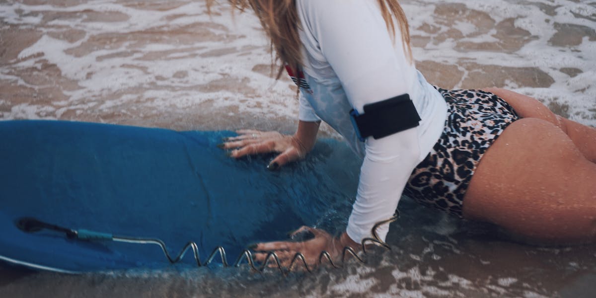 A woman in a red sweater deciding between clothes in a messy room.