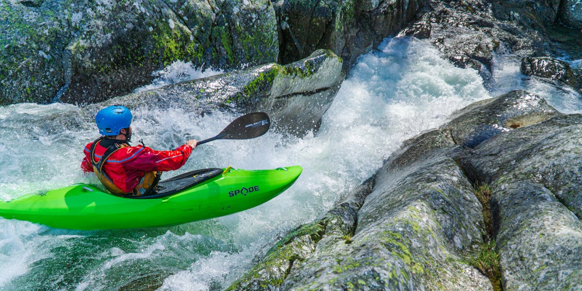 An adventurous kayaker in a bright green kayak tackles thrilling whitewater rapids...