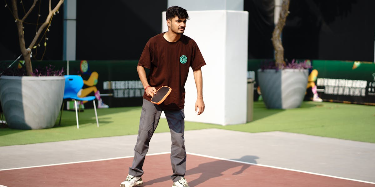 A young man actively engaged in a game of pickleball on an outdoor court.