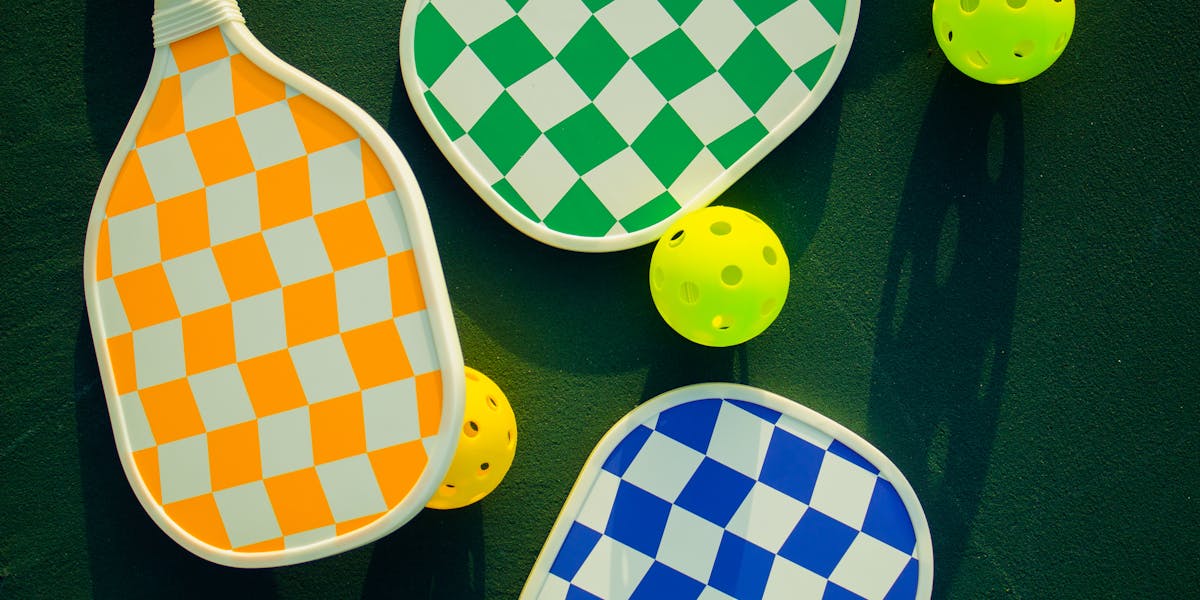 Vibrant pickleball paddles and balls arranged on a sunny sports court.