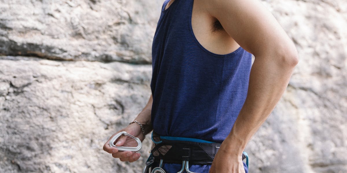Adult male preparing harness outdoors for a rock climbing adventure on a rocky t