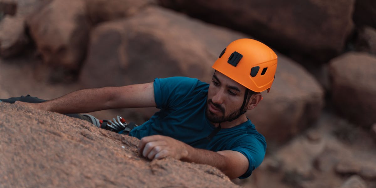 A man wearing a helmet is rock climbing, showcasing outdoor adventure and sport.