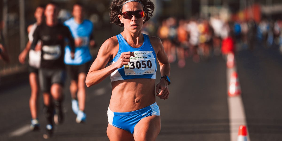 Focused female runner in blue sportswear during a marathon event outdoors.