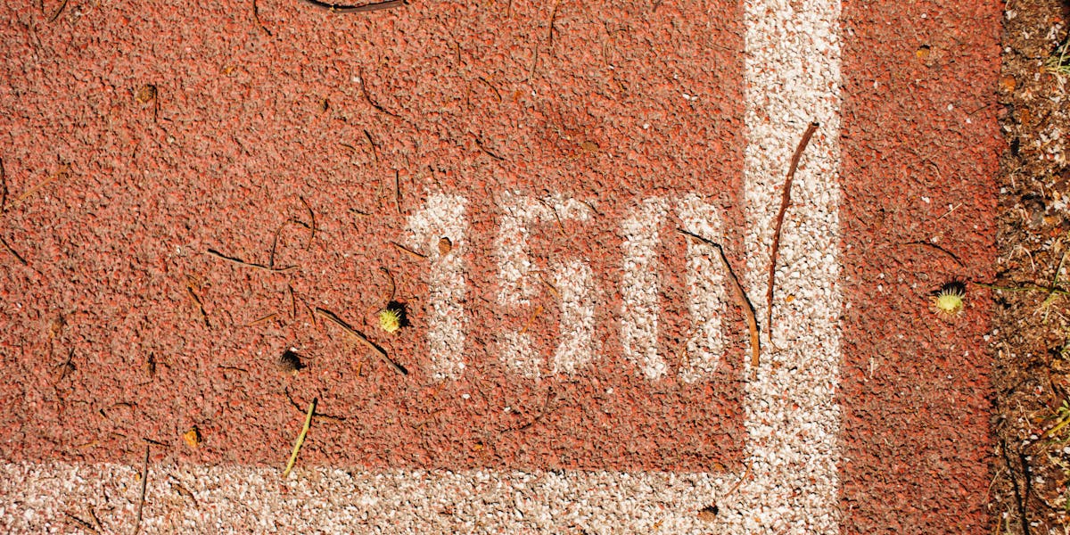 Close-up of a running track showing the number 150 marked on red surface with whit...