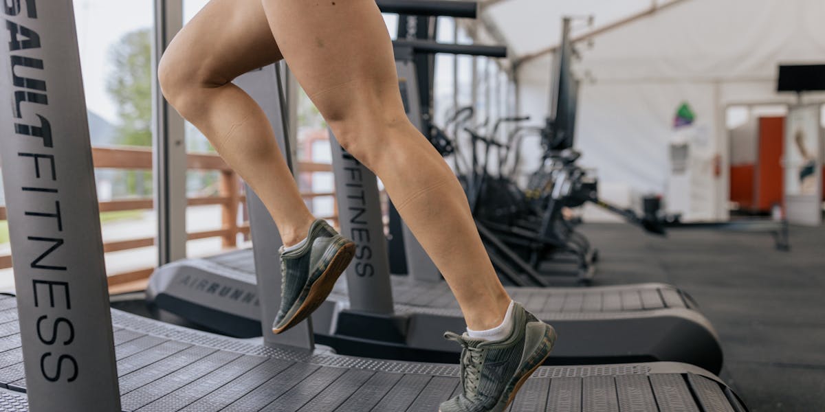 Close-up of a woman's legs running on a treadmill indoors, focusing on fitness and...