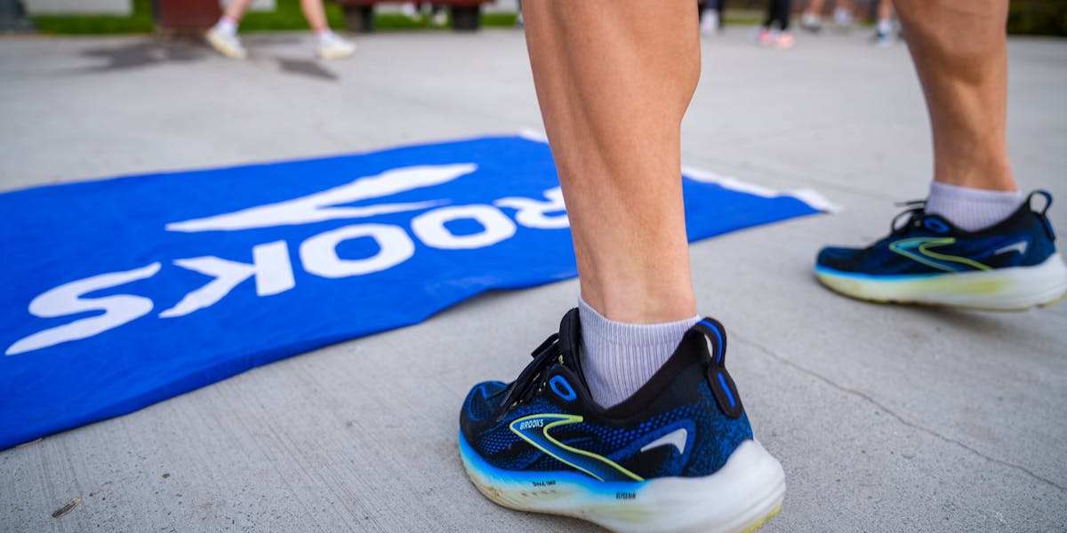 Pair of teal running shoes placed on a mossy wet surface, highlighting outdoor adv...