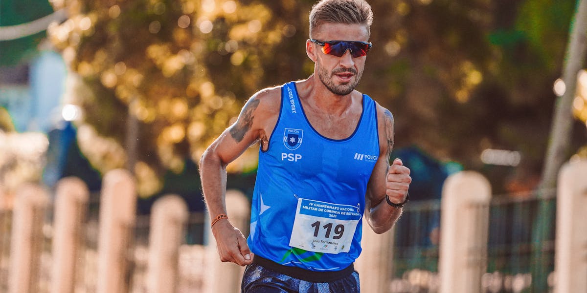 Athletic male runner wearing sunglasses participates in an outdoor race on a sunny...