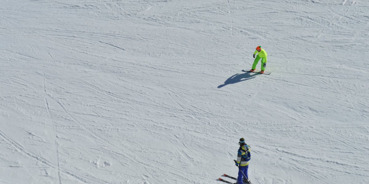 Skiers traverse a snow-covered mountain range in Chamonix, France, under clear skies.