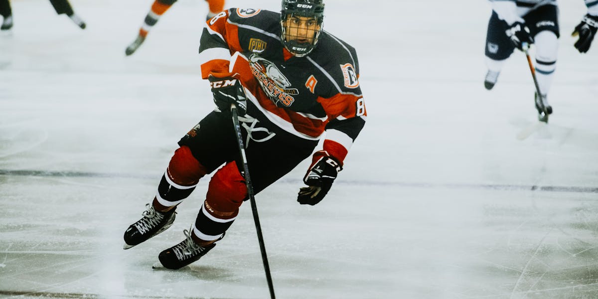 Dynamic action shot of a hockey player skating on an ice rink during a game.