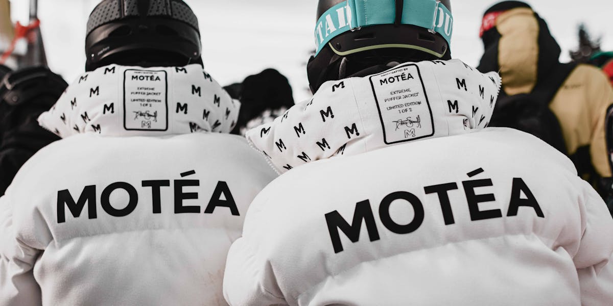 A skier in full gear poses confidently against a snowy mountain backdrop, ready 